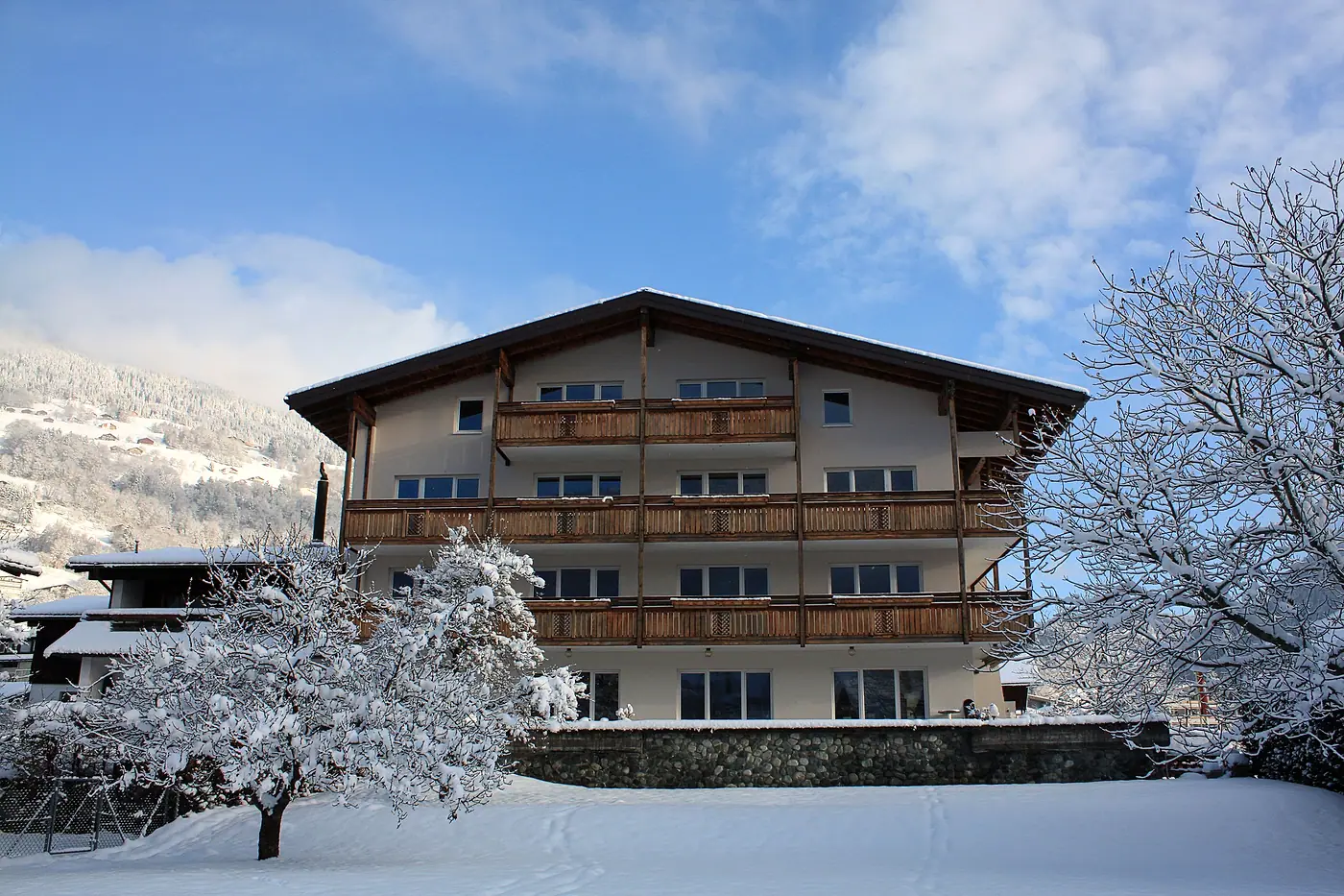 Das Hotel Chesa Platina im Winter, Holzbalkone über dem verschneiten Garten
