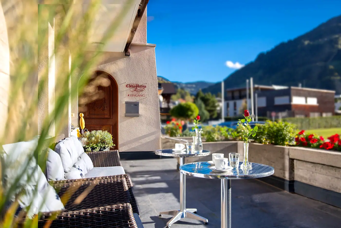 Terrasse mit Lounge, Rosen auf den Tischen und Bergen im Hintergrund